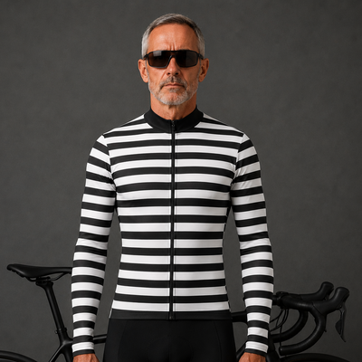 A man wearing a black and white horizontally striped long-sleeve cycling jersey and black cycling shorts stands in front of a black road bicycle against a dark gray studio background.