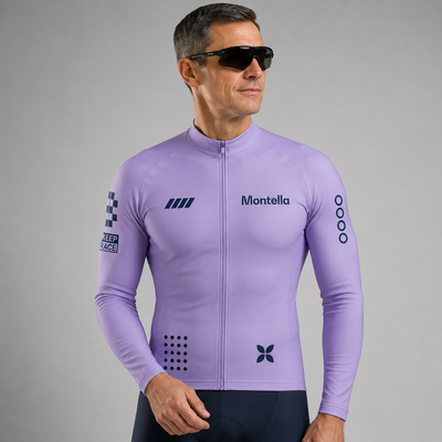 A man wearing a light purple long-sleeve cycling jersey with 'Montella' printed on the chest, black sunglasses, and dark cycling shorts, photographed against a neutral gray studio background.